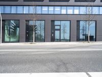 a black building with windows on the corner, and a stop sign at an intersection