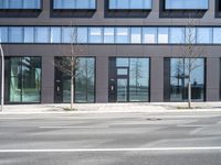 a black building with windows on the corner, and a stop sign at an intersection