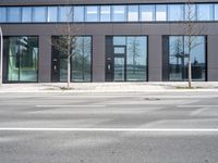 a black building with windows on the corner, and a stop sign at an intersection