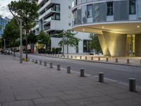 a white building with glass windows and curved walls and concrete poles with multiple lights all around it