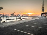 a manhole in a parking lot near the water at dusk with a cargo ship out of sight