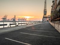 a manhole in a parking lot near the water at dusk with a cargo ship out of sight