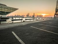 a manhole in a parking lot near the water at dusk with a cargo ship out of sight