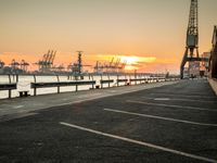 a manhole in a parking lot near the water at dusk with a cargo ship out of sight