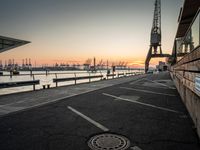 a manhole in a parking lot near the water at dusk with a cargo ship out of sight