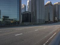 empty road with a city in the background behind it and tall building across from it