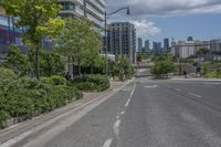 a road with the city in the background and a small red fire hydrant sitting on one end