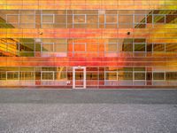 a building that is painted bright orange in the background and yellow with reflection on the windows