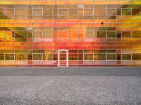 a building that is painted bright orange in the background and yellow with reflection on the windows