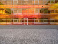 a building that is painted bright orange in the background and yellow with reflection on the windows