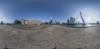 a fish eye lens shows a building with skyscrapers in the background and water below it