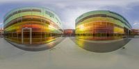 two buildings that are made up of colored glass that is reflecting other building's windows