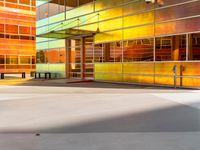 a very colorful building with glass windows and a bench by the window is very nice