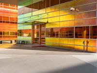 a very colorful building with glass windows and a bench by the window is very nice