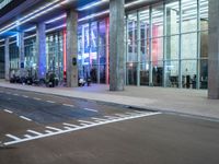 an outside view of a modern building at night with red and blue lights on the outside