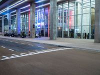 an outside view of a modern building at night with red and blue lights on the outside