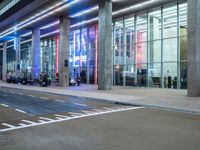 an outside view of a modern building at night with red and blue lights on the outside