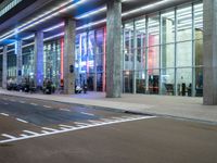 an outside view of a modern building at night with red and blue lights on the outside