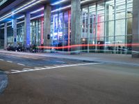 an outside view of a modern building at night with red and blue lights on the outside