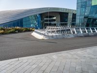 a sidewalk with concrete steps in front of an office building with glass and steel facade