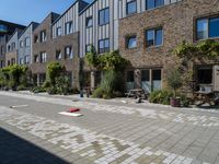 a brick road with various plants and a stuffed red piece of furniture on the side