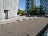 a metal bench sitting next to a building on top of a street in front of tall buildings