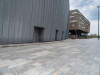 a brick sidewalk and building with windows on the side of a street in a city