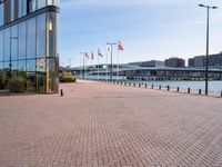 there is a brick paved walkway in front of an office building with flags flying on it