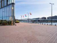 there is a brick paved walkway in front of an office building with flags flying on it