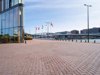 there is a brick paved walkway in front of an office building with flags flying on it