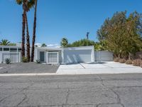 a large white home with palm trees in front of it and concrete driveway on either side