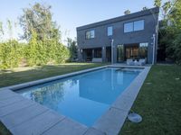 a home that is made out of concrete with a swimming pool on the lawn of the yard