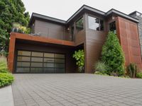 a home with wood panels and gray windows and a brick driveway and a stone paved walkway