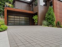 a home with wood panels and gray windows and a brick driveway and a stone paved walkway