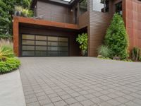 a home with wood panels and gray windows and a brick driveway and a stone paved walkway