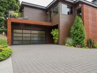 a home with wood panels and gray windows and a brick driveway and a stone paved walkway