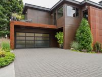 a home with wood panels and gray windows and a brick driveway and a stone paved walkway