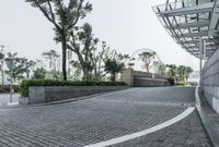 the walkway leads to a park next to a building with glass bales on it