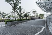 the walkway leads to a park next to a building with glass bales on it