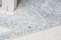 two tile wall in various shapes and colors of white and grey, with one tile floor in square pattern