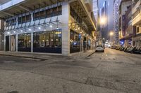 the parking lot is empty of vehicles on the street in front of the building at night