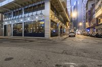 the parking lot is empty of vehicles on the street in front of the building at night