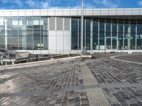 a paved area outside of an office building with a clock on it and a stairway going down to the side