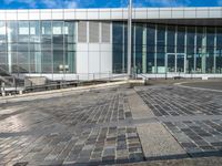 a paved area outside of an office building with a clock on it and a stairway going down to the side