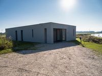 a building with a door and no windows sitting on the side of a dirt field