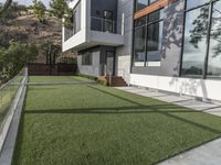 a large house with grass and concrete in front of it and a deck in the yard and on the ground below the walkway