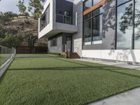 a large house with grass and concrete in front of it and a deck in the yard and on the ground below the walkway