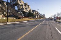 an empty street has no vehicles on it in the distance is a large building on the left side