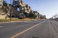 an empty street has no vehicles on it in the distance is a large building on the left side