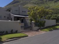 a white house with a metal fence and gate sits on the side of a road